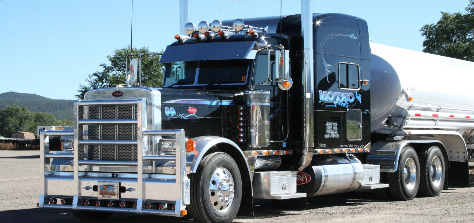 Black peterbilt 18-wheeler semi-truck with chrome details pulling a tanker trailer on a texas roadway