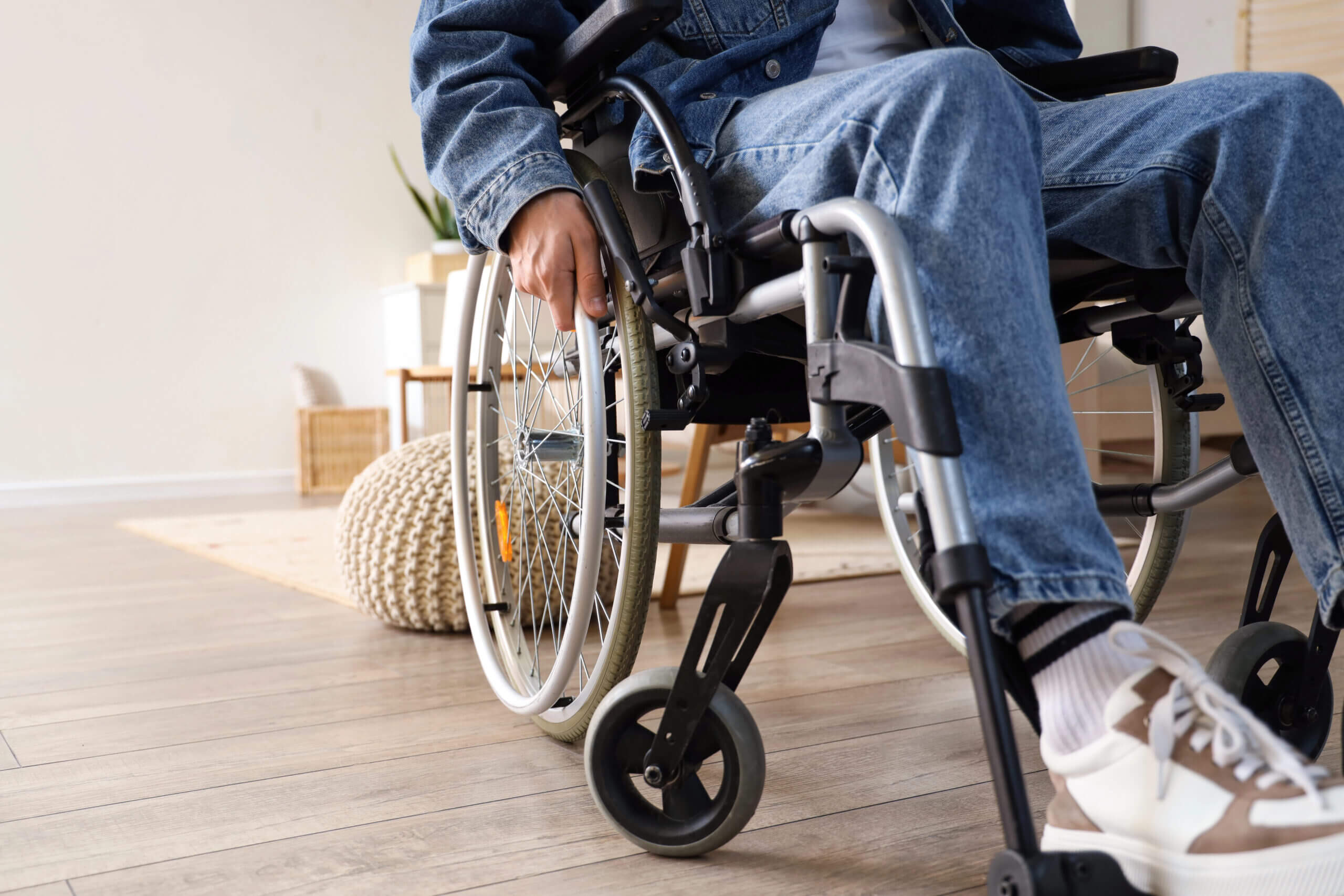A person in a denim jacket using a wheelchair inside their home, representing the permanent disability and long-term recovery challenges faced by serious truck accident injury victims.