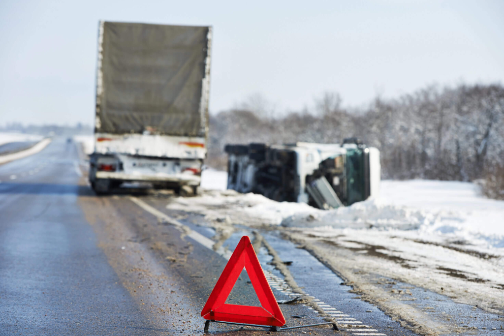 Commercial truck accident scene with overturned trailer and warning triangle illustrating evidence at the start of a commercial truck accident claim investigation.